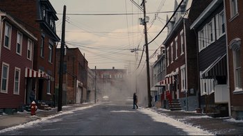 Movie still from “The Dark Knight Rises” (2012), directed by Christopher Nolan – A person walking down a street near some buildings; Extreme Wide shot, High angle