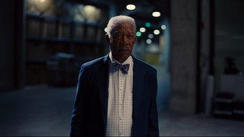 Movie still from “The Dark Knight Rises” (2012), directed by Christopher Nolan – An older man wearing a suit and a bow tie; Medium shot, Low angle