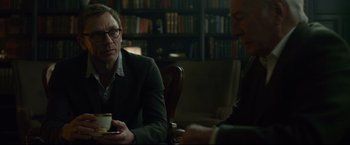 Movie still from “The Girl with the Dragon Tattoo” (2011), directed by David Fincher – Two men sitting at a table in front of a book case; Medium shot, Over the shoulder angle