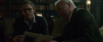 Movie still from “The Girl with the Dragon Tattoo” (2011), directed by David Fincher – Two men sitting at a table in front of a book; Medium shot, Over the shoulder angle