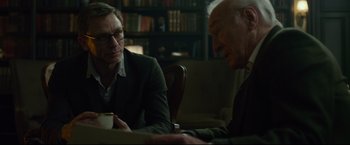 Movie still from “The Girl with the Dragon Tattoo” (2011), directed by David Fincher – Two people sitting at a table with a cup of coffee; Medium shot, Over the shoulder angle