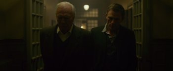 Movie still from “The Girl with the Dragon Tattoo” (2011), directed by David Fincher – Two men in suits standing next to each other in a dark room; Medium shot, Low angle