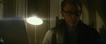 Movie still from “The Girl with the Dragon Tattoo” (2011), directed by David Fincher – A man wearing glasses standing in front of a lamp; Close Up shot, Low angle