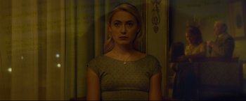 Movie still from “The Girl with the Dragon Tattoo” (2011), directed by David Fincher – A woman with blonde hair is standing in front of a curtain; Medium shot, Over the shoulder angle