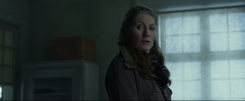 Movie still from “The Girl with the Dragon Tattoo” (2011), directed by David Fincher – A woman in a brown jacket standing in front of a window; Close Up shot, Over the shoulder angle