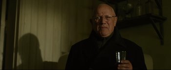 Movie still from “The Girl with the Dragon Tattoo” (2011), directed by David Fincher – An old man with glasses is holding a drink; Close Up shot, Low angle