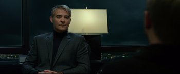 Movie still from “The Girl with the Dragon Tattoo” (2011), directed by David Fincher – A man in a suit sitting in front of a lamp in a dark room; Medium shot, Low angle