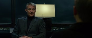 Movie still from “The Girl with the Dragon Tattoo” (2011), directed by David Fincher – A man sitting in a chair in front of a lamp; Medium shot, Over the shoulder angle