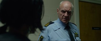 Movie still from “The Girl with the Dragon Tattoo” (2011), directed by David Fincher – An older man wearing a uniform looking at a camera; Close Up shot, Over the shoulder angle