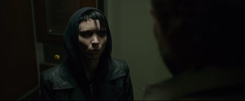 Movie still from “The Girl with the Dragon Tattoo” (2011), directed by David Fincher – A woman in a hooded jacket looking into a mirror; Close Up shot, Over the shoulder angle