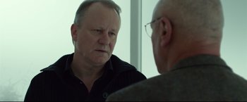 Movie still from “The Girl with the Dragon Tattoo” (2011), directed by David Fincher – A man in a black shirt is talking to another man in glasses; Close Up shot, Over the shoulder angle