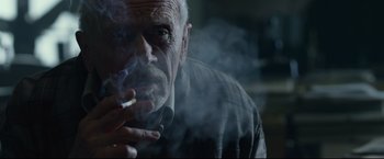 Movie still from “The Girl with the Dragon Tattoo” (2011), directed by David Fincher – An older man smoking a cigarette in front of a window; Close Up shot, Low angle