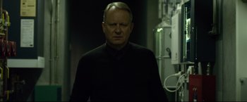 Movie still from “The Girl with the Dragon Tattoo” (2011), directed by David Fincher – An older man in a black shirt is standing in a dark room; Close Up shot, Low angle