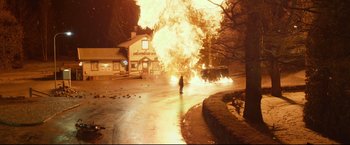 Movie still from “The Girl with the Dragon Tattoo” (2011), directed by David Fincher – A person standing in front of a car on fire; Extreme Wide shot, High angle
