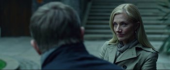 Movie still from “The Girl with the Dragon Tattoo” (2011), directed by David Fincher – A woman in a trench coat is talking to a man in front of stairs; Close Up shot, Over the shoulder angle