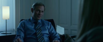 Movie still from “The Girl with the Dragon Tattoo” (2011), directed by David Fincher – A man sitting in an office chair with a cat; Medium shot, Over the shoulder angle