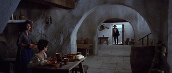 Movie still from “The Good, the Bad and the Ugly” (1966), directed by Sergio Leone – A man standing in a room next to a table; Wide shot, Low angle