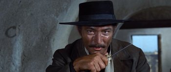Movie still from “The Good, the Bad and the Ugly” (1966), directed by Sergio Leone – A man in a black hat holding a knife; Close Up shot, High angle