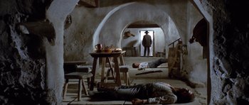 Movie still from “The Good, the Bad and the Ugly” (1966), directed by Sergio Leone – A group of people laying on the ground in a room; Wide shot, Low angle
