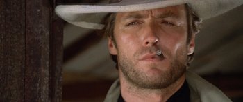 Movie still from “The Good, the Bad and the Ugly” (1966), directed by Sergio Leone – A person wearing a hat smoking a cigarette; Close Up shot, Low angle