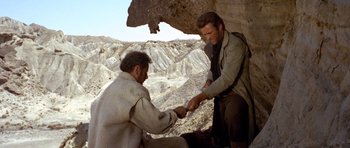 Movie still from “The Good, the Bad and the Ugly” (1966), directed by Sergio Leone – Two men in the desert one of them is holding a knife; Medium shot, Over the shoulder angle
