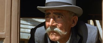 Movie still from “The Good, the Bad and the Ugly” (1966), directed by Sergio Leone – An old man with a mustache wearing a suit and a hat; Close Up shot, Low angle