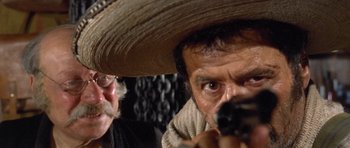 Movie still from “The Good, the Bad and the Ugly” (1966), directed by Sergio Leone – A man with a hat is holding a gun; Close Up shot, Low angle