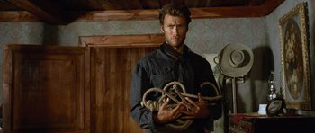Movie still from “The Good, the Bad and the Ugly” (1966), directed by Sergio Leone – A man holding a bunch of ropes in his hands; Medium shot, Low angle