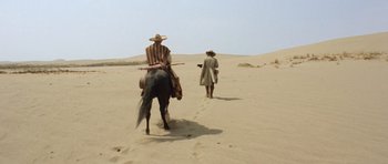 Movie still from “The Good, the Bad and the Ugly” (1966), directed by Sergio Leone – A man riding on the back of a horse in the desert; Wide shot, High angle