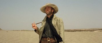 Movie still from “The Good, the Bad and the Ugly” (1966), directed by Sergio Leone – A man wearing a cowboy hat and holding a pipe; Medium shot, Low angle