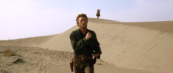 Movie still from “The Good, the Bad and the Ugly” (1966), directed by Sergio Leone – A man standing on top of a sand dune; Wide shot, Low angle