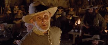 Movie still from “The Good, the Bad and the Ugly” (1966), directed by Sergio Leone – An old man wearing a hat and looking surprised; Close Up shot, Over the shoulder angle