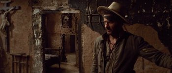 Movie still from “The Good, the Bad and the Ugly” (1966), directed by Sergio Leone – A man wearing a cowboy hat standing in a room; Medium shot, High angle