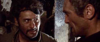 Movie still from “The Good, the Bad and the Ugly” (1966), directed by Sergio Leone – A man with a bandage on his head is talking to another man; Close Up shot, Over the shoulder angle