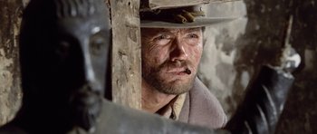 Movie still from “The Good, the Bad and the Ugly” (1966), directed by Sergio Leone – A person wearing a hat and smoking a cigarette; Close Up shot, Low angle
