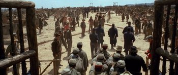 Movie still from “The Good, the Bad and the Ugly” (1966), directed by Sergio Leone – A group of men standing around in the dirt; Extreme Wide shot, Over the shoulder angle