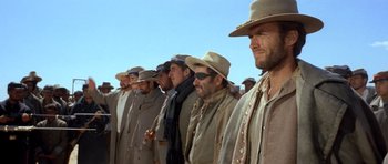 Movie still from “The Good, the Bad and the Ugly” (1966), directed by Sergio Leone – A group of men standing next to each other wearing hats; Medium shot, Low angle