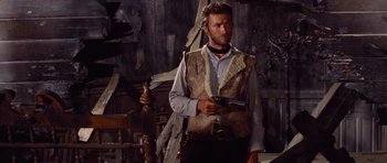 Movie still from “The Good, the Bad and the Ugly” (1966), directed by Sergio Leone – A man holding a gun while standing in a room; Medium shot, Low angle