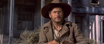Movie still from “The Good, the Bad and the Ugly” (1966), directed by Sergio Leone – A man in a hat and a jacket holding a gun; Close Up shot, Low angle