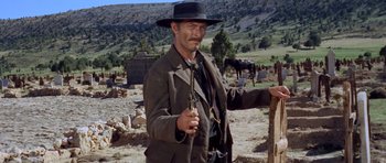 Movie still from “The Good, the Bad and the Ugly” (1966), directed by Sergio Leone – A man in a black hat holding a pair of guns; Medium shot, Low angle