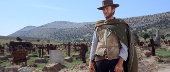 Movie still from “The Good, the Bad and the Ugly” (1966), directed by Sergio Leone – A man in a hat and vest standing in a field; Medium shot, Low angle