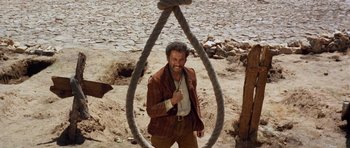 Movie still from “The Good, the Bad and the Ugly” (1966), directed by Sergio Leone – A man standing in front of a rope hanging from the ground; Medium shot, Low angle