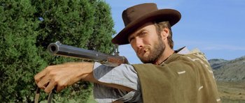 Movie still from “The Good, the Bad and the Ugly” (1966), directed by Sergio Leone – A man with a hat on holding a gun; Close Up shot, Low angle