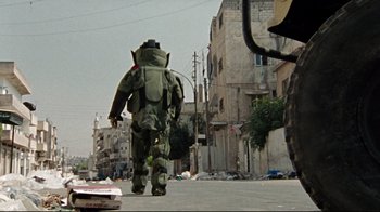Movie still from “The Hurt Locker” (2008), directed by Kathryn Bigelow – A man walking down the street wearing a backpack; Wide shot, Low angle