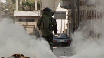 Movie still from “The Hurt Locker” (2008), directed by Kathryn Bigelow – A man walking down the street with a backpack on his back; Wide shot, High angle
