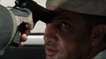 Movie still from “The Hurt Locker” (2008), directed by Kathryn Bigelow – A person with a gun in his hand; Close Up shot, Over the shoulder angle
