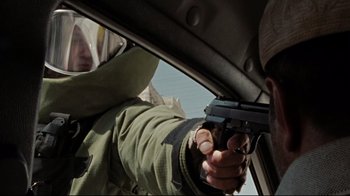 Movie still from “The Hurt Locker” (2008), directed by Kathryn Bigelow – A man holding a gun in his hand while sitting in a car; Close Up shot, Over the shoulder angle