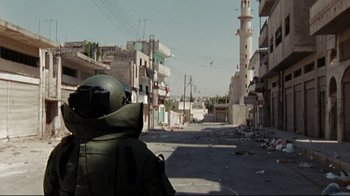 Movie still from “The Hurt Locker” (2008), directed by Kathryn Bigelow – A man in a helmet is standing in the middle of an empty street; Wide shot, High angle