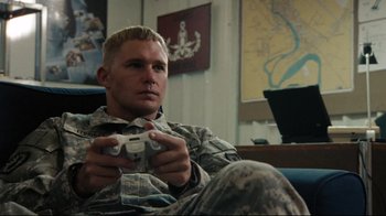 Movie still from “The Hurt Locker” (2008), directed by Kathryn Bigelow – A man sitting on a couch holding a game controller in his hands; Close Up shot, High angle