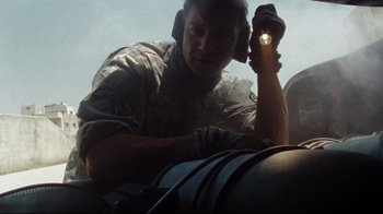 Movie still from “The Hurt Locker” (2008), directed by Kathryn Bigelow – A man in fatigues is holding a flashlight in his hand; Medium shot, Low angle